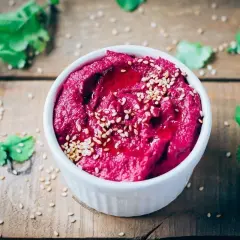 Hummus de remolacha, una de las mejores remolacha recetas, adornado con semillas de sésamo y un chorrito de aceite.