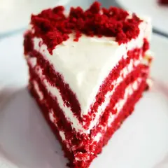 En saftig bit red velvet cake med fluffig frosting och smulor på toppen.