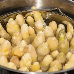 Spargel im Spargeltopf kochen. Die weißen Stangen garen in siedendem Wasser, bereit für ein köstliches Gericht.