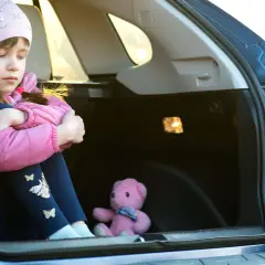 Traurige Kinder im Kofferraum, nur ein Teddybär als Gesellschaft.