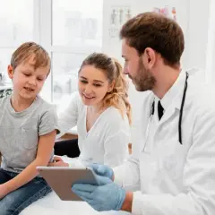 Medico di famiglia: gli orari, le nuove regole. Un dottore mostra un tablet a un bambino e sua madre, spiegando le novità.