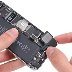 Dłonie trzymają otwarty telefon, wyjmując głośnik. Dowiedz się, jak sprawdzić głośnik w telefonie, gdy masz dostęp do jego wnętrza.