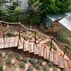 Eine **einfache Gartentreppe selber bauen** ist hier gelungen. Holzstufen führen durch Lavendel und Steine, ein Seilgeländer sorgt für Halt.