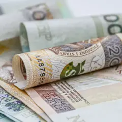 Zwijane polskie banknoty, w tym 20 złotych, symbolizują oszczędności na dodatkowy urlop.