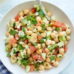 Ensalada de garbanzos fresca con tomate, pepino, aceitunas y perejil, lista para disfrutar.