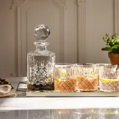 Elegancka karafka i cztery kieliszki z napojem, każdy o pojemności ok. 150 ml, gotowe do degustacji.
