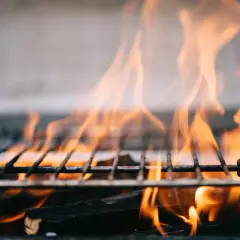 Płomienie tańczą nad rusztem, pokazując, jak rozpalic grilla. Drewno żarzy się, tworząc idealne warunki do grillowania.