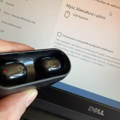 Słuchawki bezprzewodowe w etui, gotowe do połączenia z wieżą. Na ekranie komputera widać ustawienia urządzeń USB.