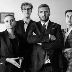 Cztery osoby w garniturach stojące w rzędzie, dwie kobiety i dwóch mężczyzn.