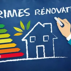 Une main dessine une maison sur un tableau bleu, avec une échelle d'efficacité énergétique et le texte "PRIMES RÉNOVATION".