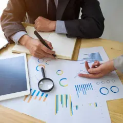 Deux personnes analysent des graphiques et des données pour un audit énergétique. Un ordinateur portable et une tablette sont sur la table.