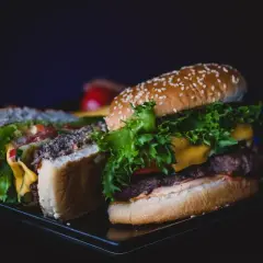 Pyszny kurczak burger mc, przekrojony na pół, z soczystą sałatą, serem i pomidorami.