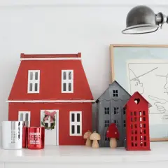 Un pueblo de casitas de navidad de madera, con una casa roja grande y otras más pequeñas, adornos y velas.