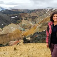 Uśmiechnięta kobieta na tle barwnych gór Landmannalaugar na Islandii.