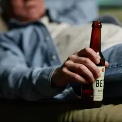 Mężczyzna odpoczywa z butelką piwa, zastanawiając się nad metabolizmem alkoholu.