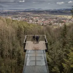 Dwie osoby stoją na szklanym tarasie widokowym, podziwiając panoramę Starego Sącza. To jedna z głównych atrakcji turystycznych regionu.