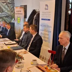 Ludzie siedzący przy stole podczas spotkania, na ścianie banery "Lubelska Izba Rolnicza" i "TUW Ubezpieczenia".