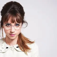 Ein junges Mädchen mit einem Dutt und Pony, das eine runde Brille trägt. Ihre Frisur mit Brille ist ein echter Hingucker.