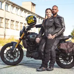 Para motocyklistów w skórzanych ubraniach siedzi na motocyklu Indian, obok stoi kask.