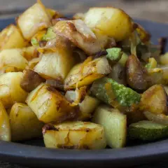 Un piatto invitante di patate e zucchine al forno, dorate e saporite, pronte per essere gustate.