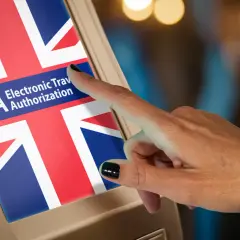 Dłoń dotyka ekranu z flagą Wielkiej Brytanii i napisem ETA Electronic Travel Authorization.