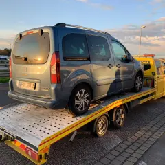 Niebieski Citroen Berlingo na żółtej lawecie. Pomoc drogowa HDI assistance w akcji, holowanie pojazdu po awarii.