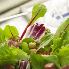 Ensalada fresca con brotes tiernos, nueces y trozos de jamón.