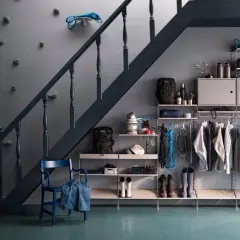 Praktische Garderobe unter der Treppe mit Klettergriffen an der Wand, Jacken, Rucksäcken und Stiefeln.