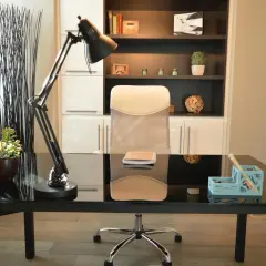 Nowoczesne biuro inspiracje: czarne biurko, wygodny fotel, lampa i regał pełen książek i dekoracji.