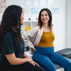 Une femme enceinte discute avec une kinésithérapeute. Elle pourrait être là pour une rééducation périnée césarienne.