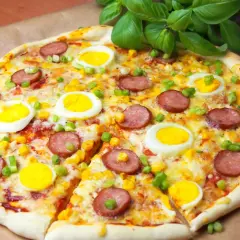 Apetyczna pizza z jajkiem, kiełbasą i kukurydzą, posypana szczypiorkiem. Idealna na szybki obiad.