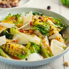 Deliciosa ensalada de cogollos a la parrilla, cubierta con lascas de queso parmesano y un aderezo vibrante.