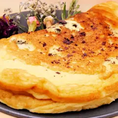 Puszysty omlet dla niemowlaka, delikatnie przyrumieniony, z ozdobnymi suszonymi kwiatami na talerzu.