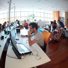 Ludzie pracujący w nowoczesnym biurze przy biurkach z komputerami.