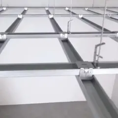 Metalowy stelaż krzyżowy na skosach, przygotowany do montażu białych paneli sufitowych.
