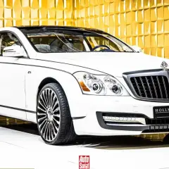 Biały Maybach 57 S z czarnym dachem i felgami, lśniącym na tle złotej, geometrycznej ściany.
