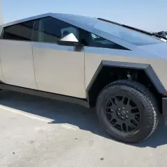 Futurystyczny Tesla Cybertruck na tle betonowego placu. Zastanawiasz się nad jego ceną?