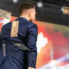 Mężczyzna w garniturze z banknotami na plecach. To wizualizacja programu partii politycznej przykłady, pokazująca inflację.