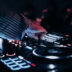 Dłoń DJ-a kręci gałką miksera, tworząc muzykę na wesele. Zastanawiasz się, ile kosztuje dj na wesele?