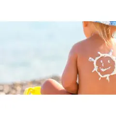 Bambino con crema solare a forma di sole sulla schiena, al mare. Protezione per la dermatite atopica e il sole.