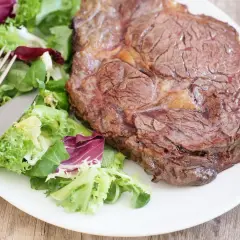 Une belle côte de bœuf, parfaitement saisie, accompagnée d'une salade fraîche. La cuisson est idéale pour un plat savoureux.
