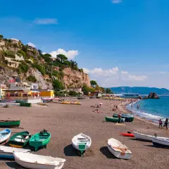 Spiagge Vietri sul Mare con barche sulla sabbia scura e case aggrappate alla scogliera.