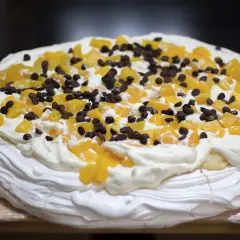 En härlig anna pavlova tårta med vispgrädde, persikobitar och chokladknappar.