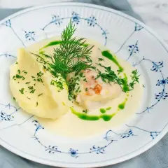 En vacker tallrik med torskrygg recept, serverad med krämigt potatismos och en grön dillolja.