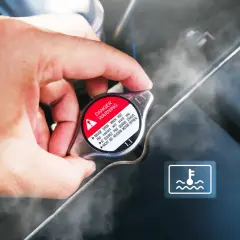 Dłoń dotyka gorącego oznaczenia wlewu płynu do chłodnicy, z którego wydobywa się para. Widoczny symbol ostrzegawczy.
