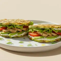 Zwei köstliche low carb sandwiches mit Zucchini-Patties, Avocado, Tomate, Tofu und Salat auf einem Teller.