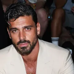 Uomo con capelli sfumati corti, barba curata e un completo chiaro.