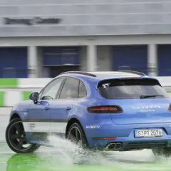 Niebieski Porsche Macan Turbo na mokrym torze Driving Center, rozpryskuje wodę. DSC co to? System stabilizacji toru jazdy.