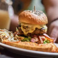 Ogromny burger z rozpływającym się serem, chrupiącym boczkiem i surówką. Wygląda jak posiłek dla prawdziwego drwala!