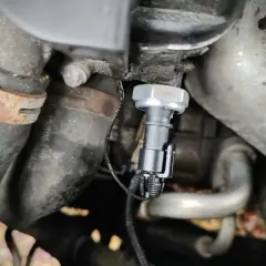 Czujnik ciśnienia oleju 2.0 TDI znajduje się w pobliżu metalowych rur i przewodów silnika.